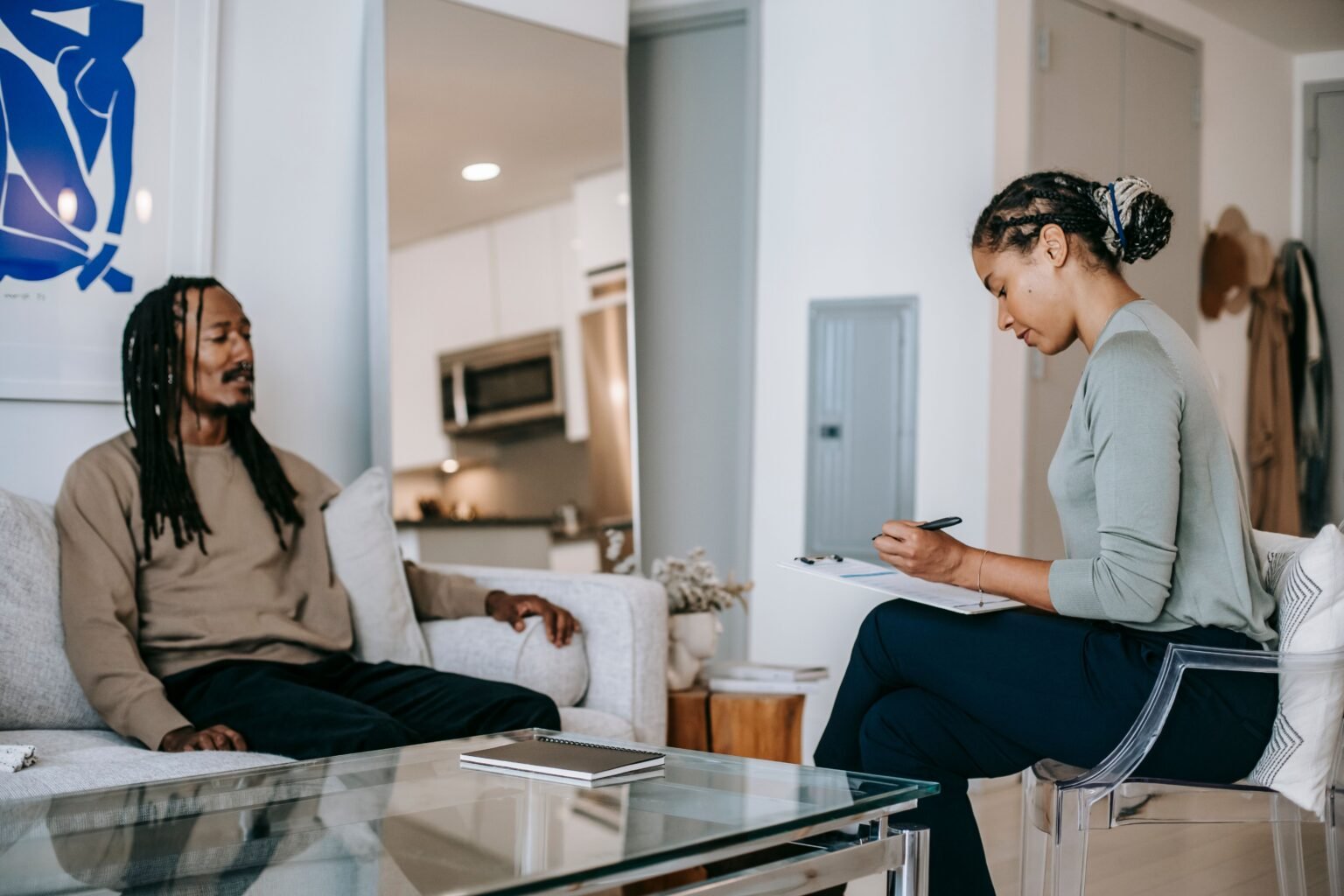 Counselor taking notes on a clipboard while her client speaks