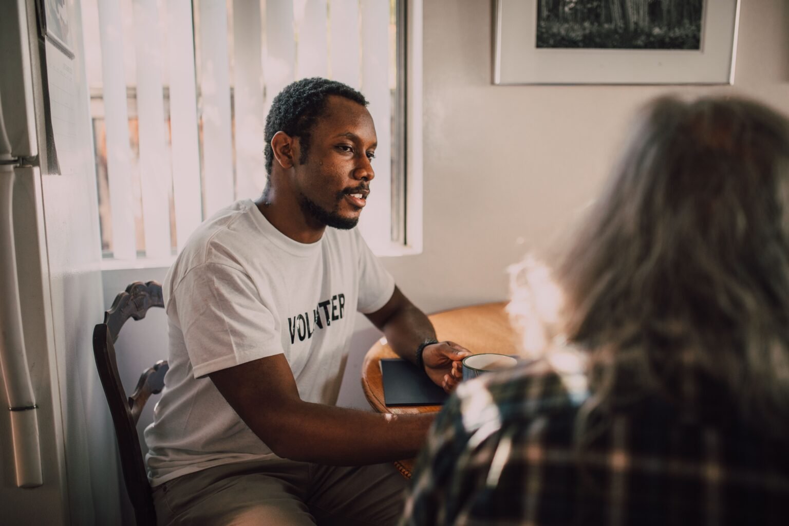 A peer support volunteer listening during a conversation over coffee