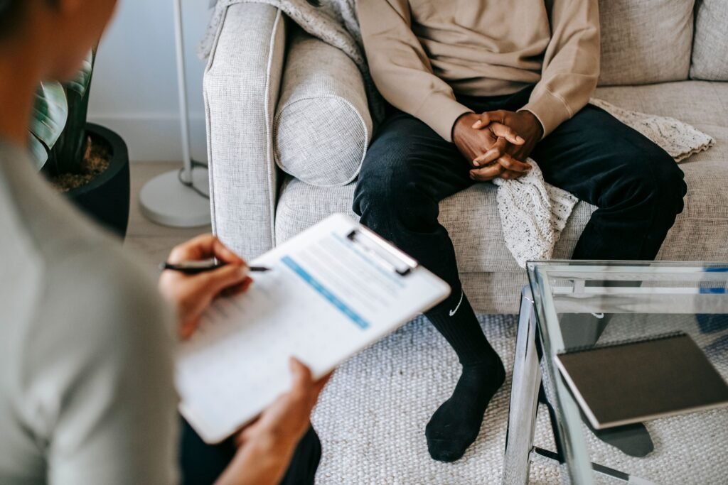 Therapist taking notes on a clipboard during a counseling session with a seated client