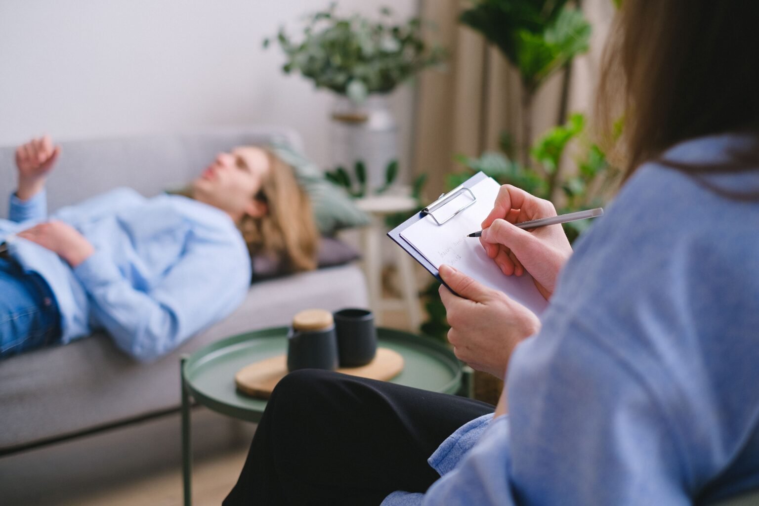 Therapist writing a treatment plan on a clipboard during a one-to-one session